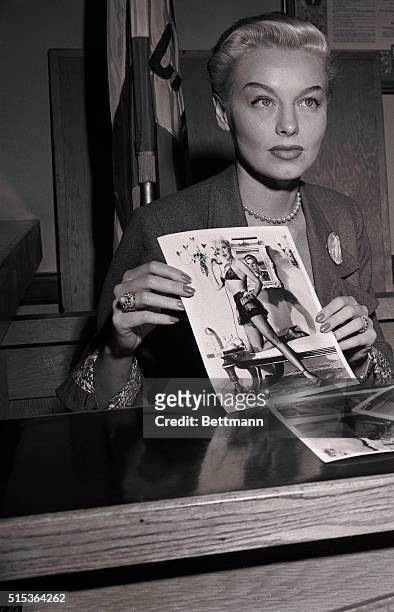 Blond dancer Lili St. Cyr shows a predominantly female jury a photograph of herself wearing the costume in which she was arrested for giving a lewd...