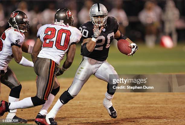 Justin Fargas of the Oakland Raiders runs with the ball against Ronde Barber of the Tampa Bay Buccaneers on September 26, 2004 at Network Associates...