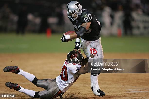 Justin Fargas of the Oakland Raiders runs with the ball as he looks to break free of the tackle by Ronde Barber of the Tampa Bay Buccaneers on...
