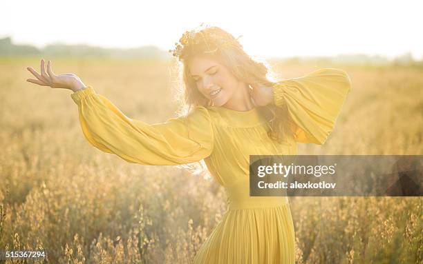 glückliche frau in felder mit sonnenlicht - haarkranz stock-fotos und bilder