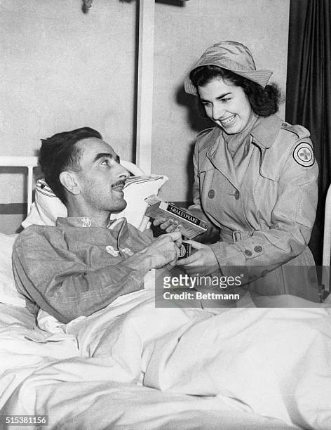 Lois White, Minneapolis, who is attached to the Red Cross Comforts unit, offers William B. Allison, Ottem, N.C., a volume of Shakespeare. Miss White...