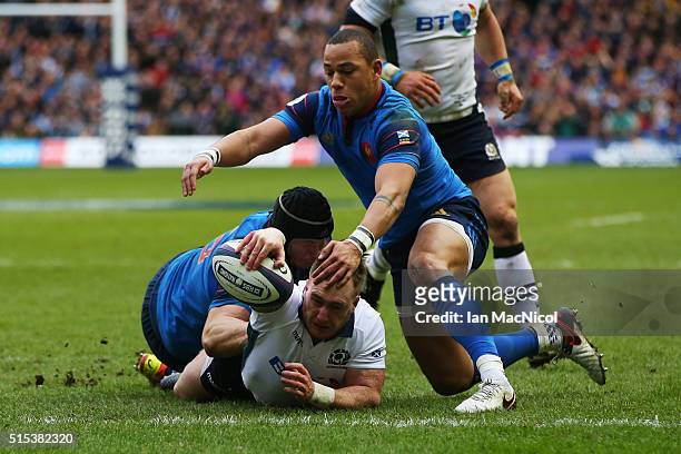 Stuart Hogg of Scotland dives through the tackles from Yacouba Camara and Gael Fickou of France to score his team's opening try during the RBS Six...
