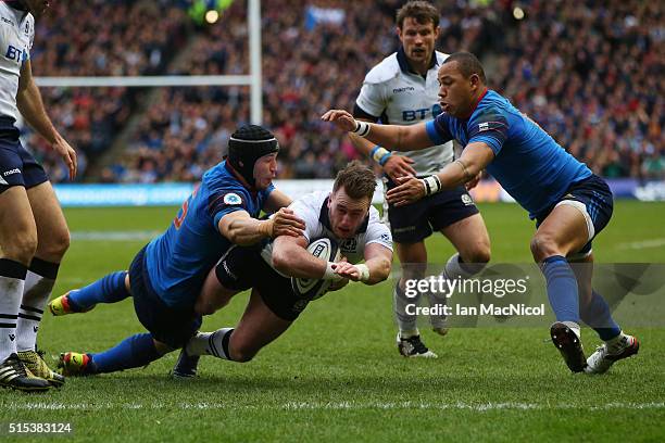 Stuart Hogg of Scotland dives through the tackles from Yacouba Camara and Gael Fickou of France to score his team's opening try during the RBS Six...