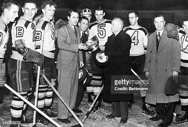 The victorious Boston Bruins are presented the Stanley Cup after defeating the Detroit Red Wings four games in a row. Weston Adams, president of the...