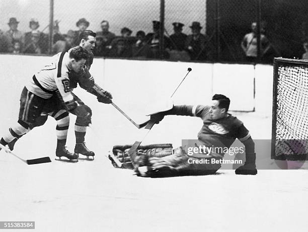 Bobby Bauer, Boston forward, has just fired the puck past goalie Johnny Mowers of the Detroit Red Wings to score the goal that clinched the Stanley...