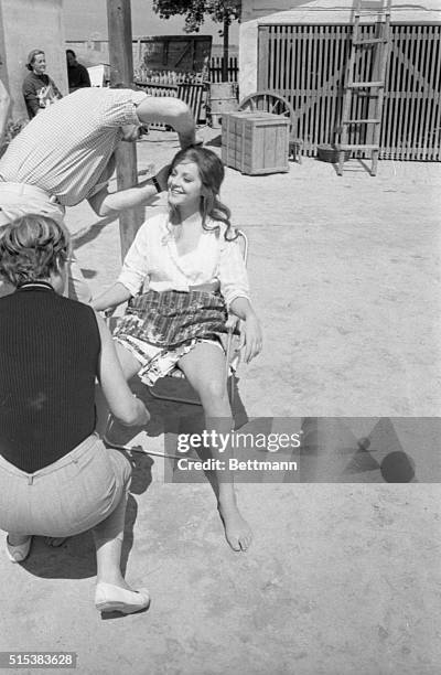 Lovely Italian actress Virna Lisi, not one to waste time, gets both a suntan and a makeup job while waiting to go on camera for the MGM film, ‘The...