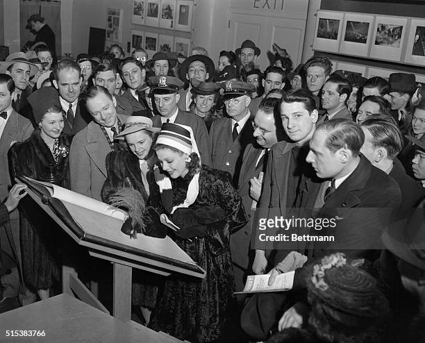 Movie stars Lee Tracy, Judy Garland, and Loretta Young, left to right, sign the register as they visit the annual exhibition of the of the Press...