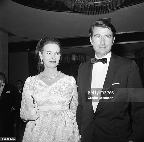 Mrs. Wyatt Cooper, better known as Gloria Vanderbilt, peeks over the shoulder of her husband and gives the cameraman a big smile as she arrives at...