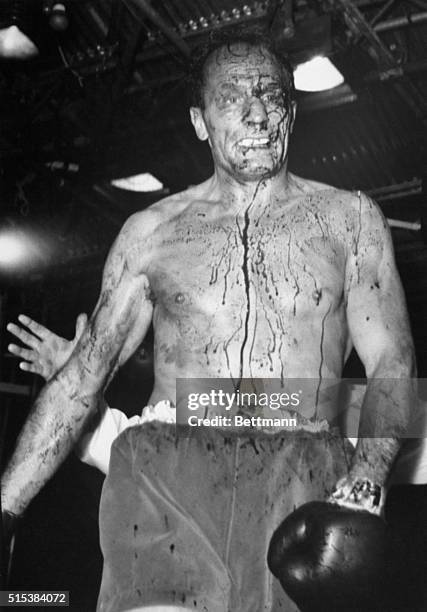 His face and chest are covered with blood as British challenger Henry Cooper heads for his corner after his title bout against heavyweight champ...
