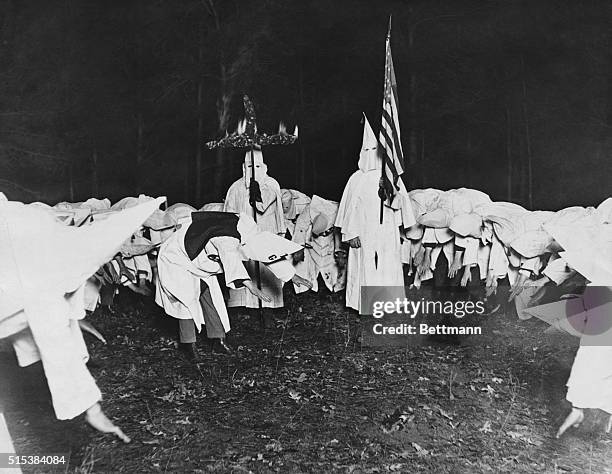 Knights of the Klu Klux Klan saluting the American flag and the fiery cross, inseparable symbols of the order.