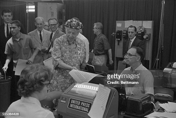 Mrs. Eleanor Roosevelt reads from a piece of wire copy, carrying convention news, from a teletype machine during her visit to United Press...