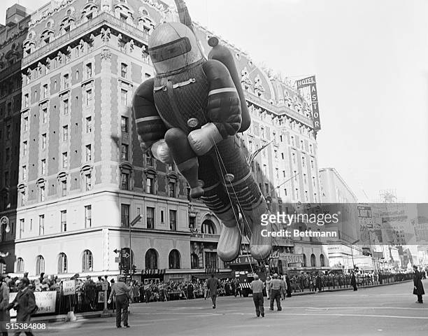 New York: Thanksgiving Day - Macy's Parade. Spaceman Balloon Held Up By Crane Moves Down Broadway. Towering Spaceman balloon, held by crane, wins...