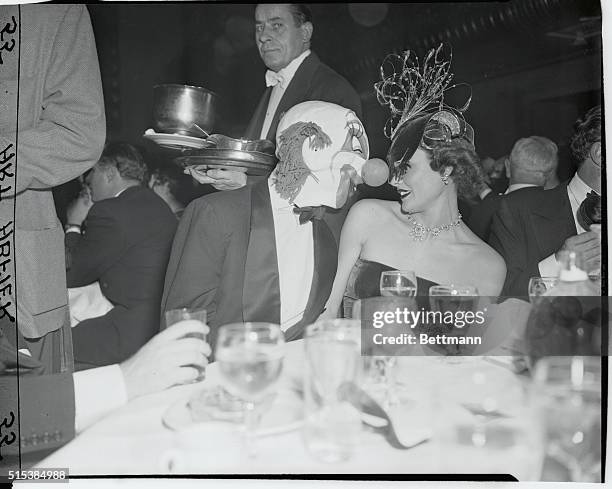 Among those present at the Bal Masque Ball at Waldorf Astoria was Movie Star Gene Tierney and her husband Oleg Cassini who is teasing her with his...