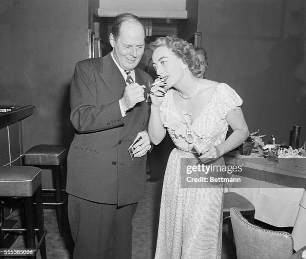 Stork Club Party for Joan Crawford. New York, New York: Sherman Billingsley, the perfect host, lights a cigarette for Miss Joan Crawford at party in...