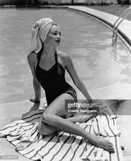 "Dickie," a famous model, sitting poolside in her bathing suit with towel wrapped around her head, turban-style. Undated photograph.