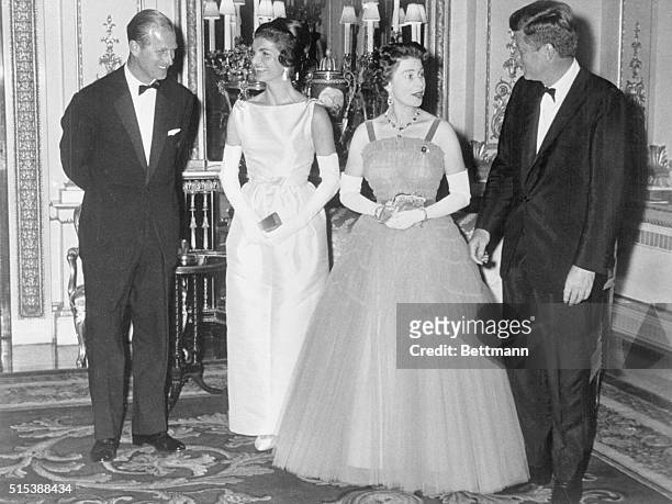 Prince Philip, Jacqueline Kennedy, Queen Elizabeth, and President John F. Kennedy chat after dinner at Buckingham Palace.