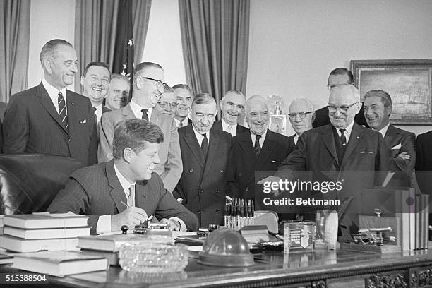 President Kennedy signs into law a $600-billion measure to aid Latin America. Present at the signing are : Vice President Lyndon B. Johnson,...