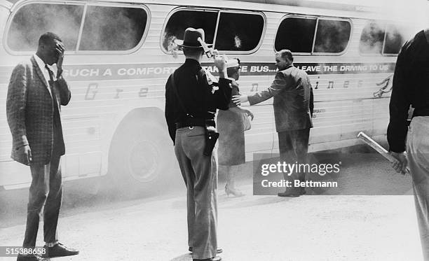 State highway patrolmen stand guard over burning Greyhound bus with clubs and drawn guns, near Anniston, Alabama, May 14 after a mob of white...
