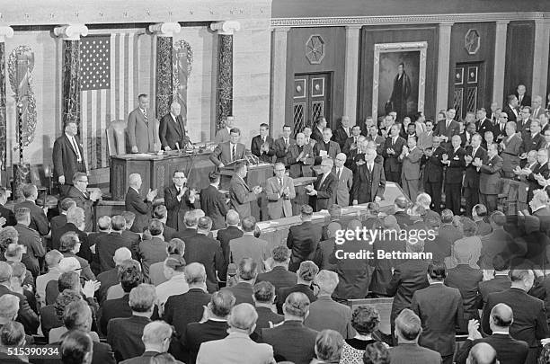 Washington: President Kennedy receives an ovation as he arrives in the House Chamber to address a Joint Session of Congress. Standing at left are...