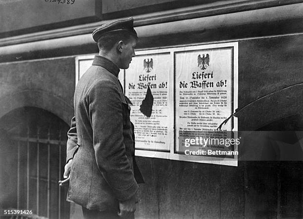 Berlin, Germany- A German policeman reading a proclamation posted in Berlin calling on the people's accordance with the terms of the Peace Treaty, to...