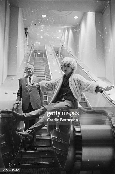 New Waldorf-Astoria Escalator. New York: Perched on rail, comedienne Carol Channing gets a big kick out of ride as she and Conrad N. Hilton,...