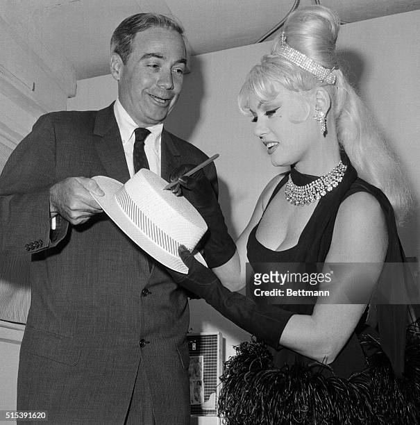Pennsylvania Governor William Scranton casts an admiring glance as Hollywood starlet Mamie Van Doren autographs his straw skimmer in her dressing...
