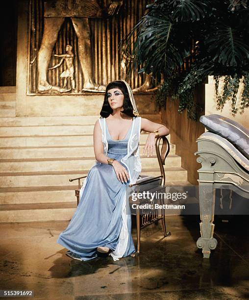 Rome, Italy: Elizabeth Taylor as Cleopatra, is shown seated on a chair in front of a stairwell, on the set in Rome where the movie is being shot.