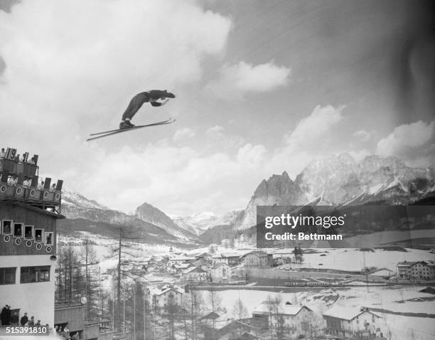 Here is a striking view of the ski jump at Cortina with a Finnish contestant soaring, seemingly, among the clouds that overhang the mountains. In the...