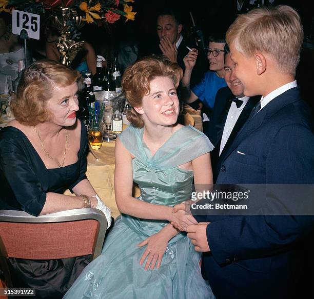 Sixteen year old Patty Duke, , smiles happily at admirers along with old timer Bette Davis after Miss Duke won the coveted Supporting Actress award...