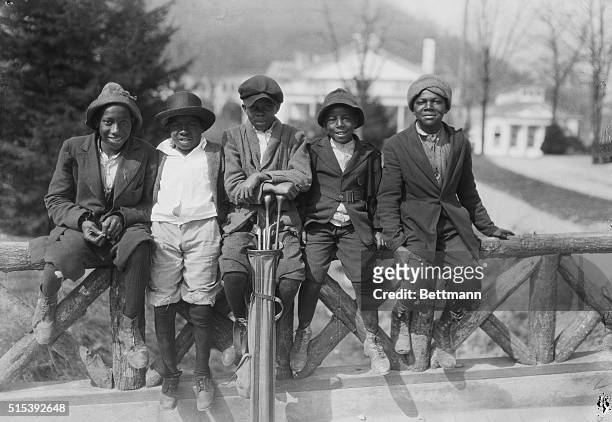 Group of young golf caddies from the 1920s sit together on a railing at The Homestead Resort in Hot Springs, Virginia..