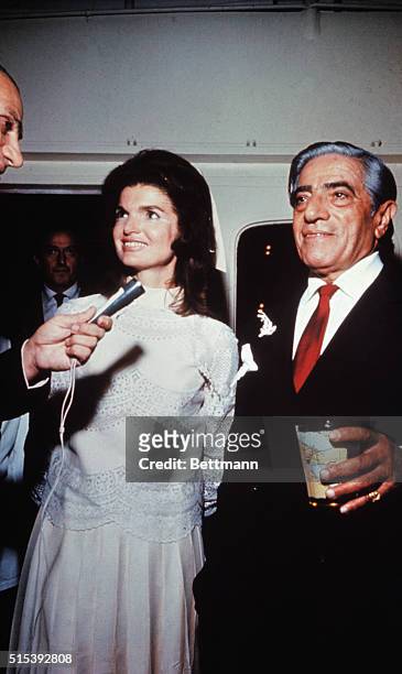 Aristotle Onassis married Jackie Kennedy on his private island. Onassis is shown with a drink in his hand and Jackie is smiling and talking into a...