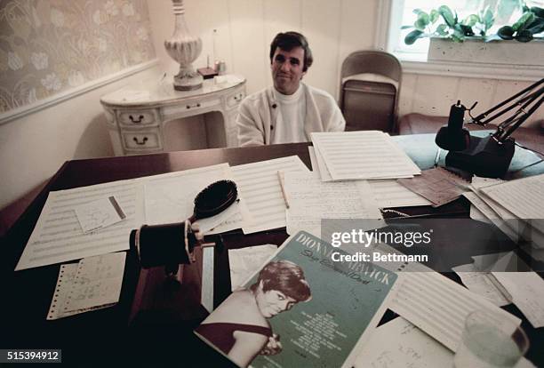 Composer Burt Bacharach plays the piano in Hollywood home June 3rd, while his wife, actress Angie Dickinson stands by.