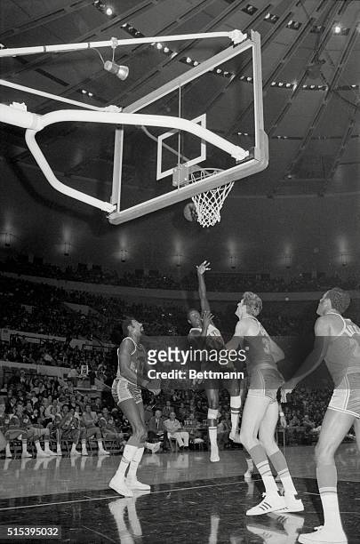 Willis Reed of the New York Knicks shoots the ball while Wilt Chamberlain and Mel Counts of the Los Angeles Lakers watch during play at Madison...
