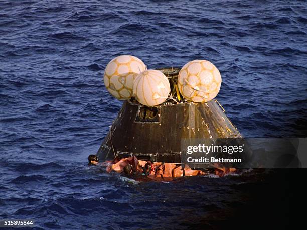 Navy swimmers fasten a floatation collar around the Apollo 13 capsule as it floats after splashdown in the Pacific Ocean. Aboard are James Lovell,...