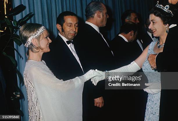 London: Queen Elizabeth II, wearing sleeveless pale blue gown, shakes hands with British born singer Petula Clark at premiere of Goodbye, Mr. Chips,...