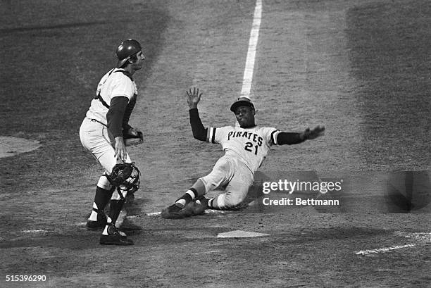 Pittsburgh Pirates' Roberto Clemente slides home in the seventh inning with the first run of the 9/10 game. Clemente scored all the way from second...