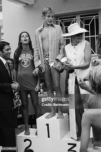 Family Swimming Relay Winners. Monaco: Princess Grace holds her daughter Stephanie's cup as she poses on the podium at the Monte Carlo Beach with her...