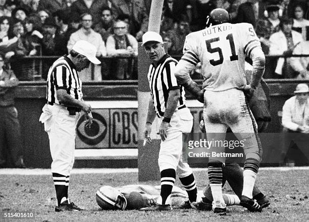 Detroit Lions' wide receiver Chuck Hughes lies on the field at Tiger Stadium, October 24, as the Chicago Bears' Dick Butkus and two officials await...