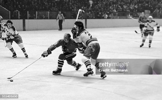 Bobby Hull , of the Chicago Black Hawks and Brad Park , New York Rangers, are shown scrambling for the puck.