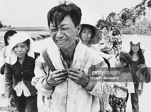March 29, 1975 - Van Ninh, South Vietnam: Carrying only a few things on his back, a weeping head of a family leads the way while walking along...