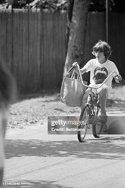 Young John Kennedy, son of the late president John F. Kennedy, rides bicycle near his summer home on way to the beach.