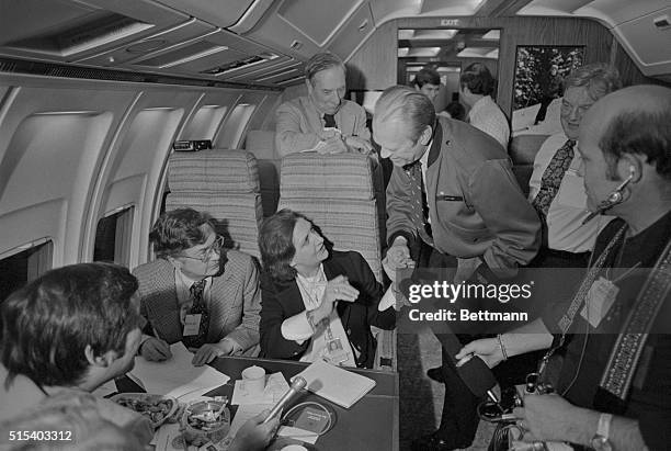 President Ford visiting the Press Section aboard Air Force One, leans in to respond to a question by UPI's Helen Thomas. The President is in Palm...