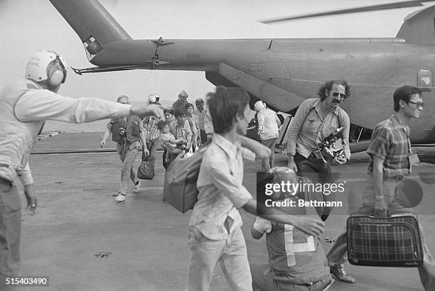 Aboard USS Okinawa: Evacuees from Saigon rush to the way as U.S. Navy man directs as they fled from South Vietnamese capital to the USS Okinawa in...