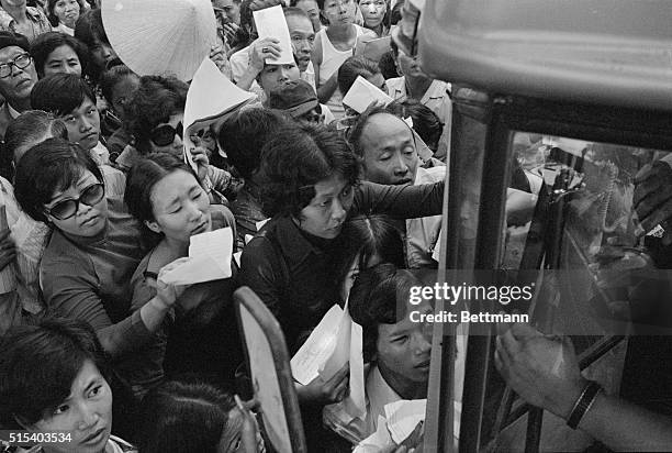 Waving their credentials, crowd of South Vietnamese citizens gather around US Embassy bus outside the facility here April 24 as they try to get on...