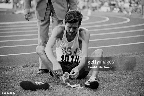 Munich, Germany: American marathon gold medal winner, Frank Shorter , removing bandage from his right foot behind finish line in Olympic Stadium...