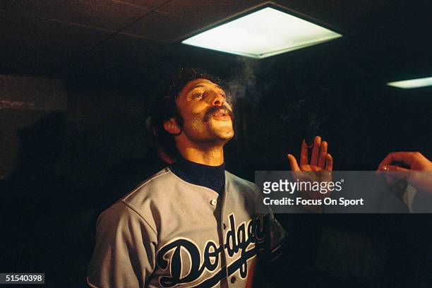 Ken Landreaux of the Los Angeles Dodgers smokes a cigar in the winner's clubhouse after defeating the Yankees during the World Series at Yankee...