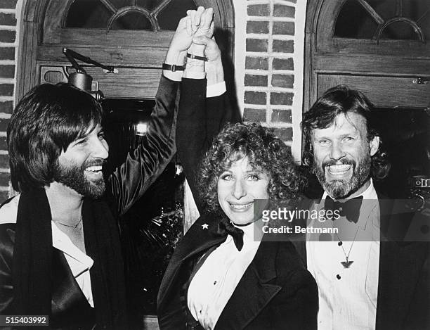 New York: Barbra Streisand and Kris Kristofferson , stars of A Star Is Born, and Lon Peters the film's producer, join hands at the party 12/23 in...