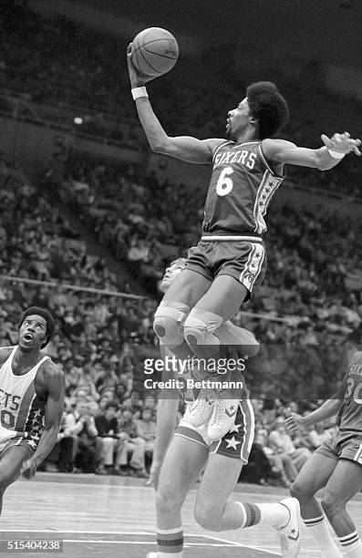 Philadelphia 76ers' Julius Erving has a high time driving in for a shot at the basket as Chuck Terry of the New York Nets comes in under the Erving...