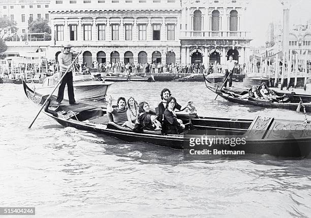 Paul McCartney and his wife, Linda, seated in back of gondola as they and other members of McCartney's "Wings" pop group go for ride on canal here...
