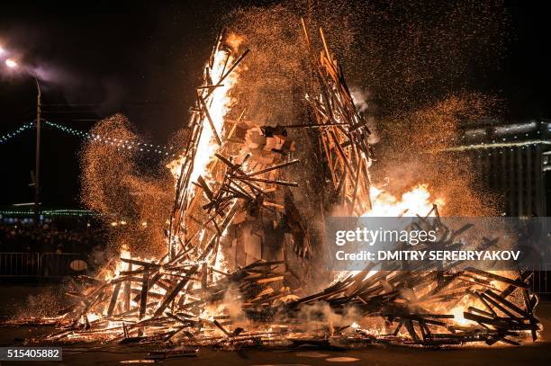 People watch a berloga dummy with 3,5-meter steel bear inside burning down during celebrations of Maslenitsa , a farewell ceremony to winter in...